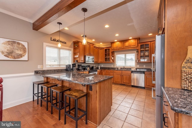 kitchen featuring sink, dark stone countertops, a kitchen bar, kitchen peninsula, and stainless steel appliances