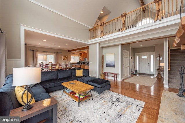 living room with light wood-type flooring and a towering ceiling