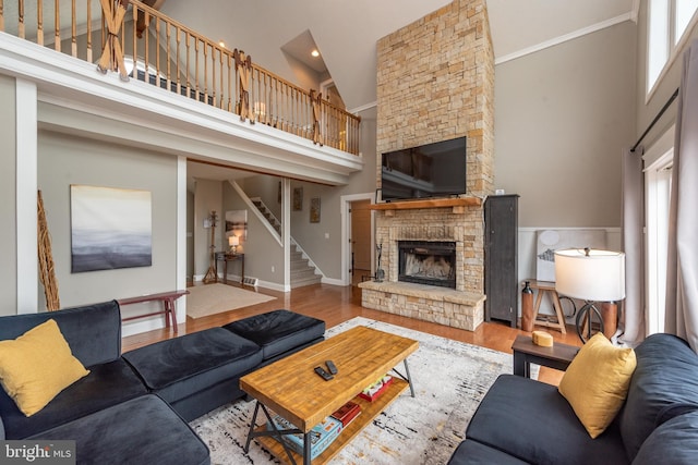 living room featuring hardwood / wood-style floors, a stone fireplace, and a towering ceiling