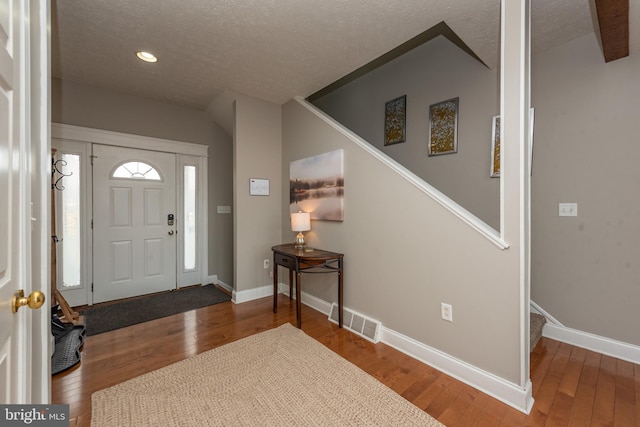 entryway featuring wood-type flooring, a textured ceiling, and beam ceiling