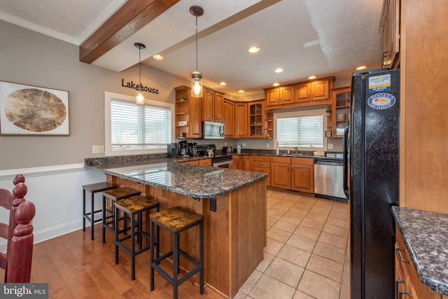 kitchen featuring stainless steel appliances, a kitchen breakfast bar, kitchen peninsula, crown molding, and dark stone countertops