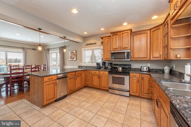 kitchen with pendant lighting, sink, a wealth of natural light, appliances with stainless steel finishes, and kitchen peninsula