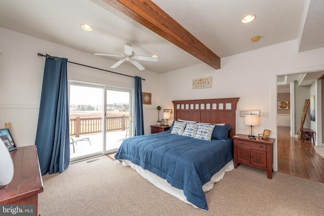 bedroom with access to outside, ceiling fan, beamed ceiling, and light colored carpet