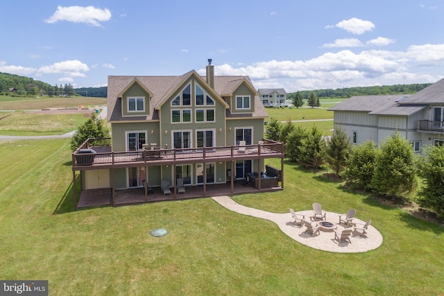 rear view of house featuring a lawn, a patio area, a deck, and an outdoor fire pit