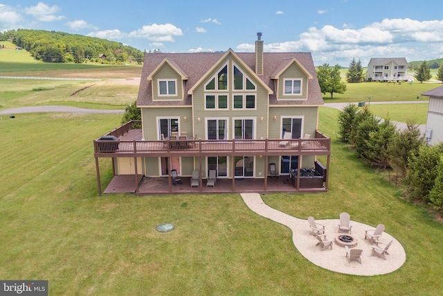 back of house featuring a yard, a deck, an outdoor fire pit, and a patio area