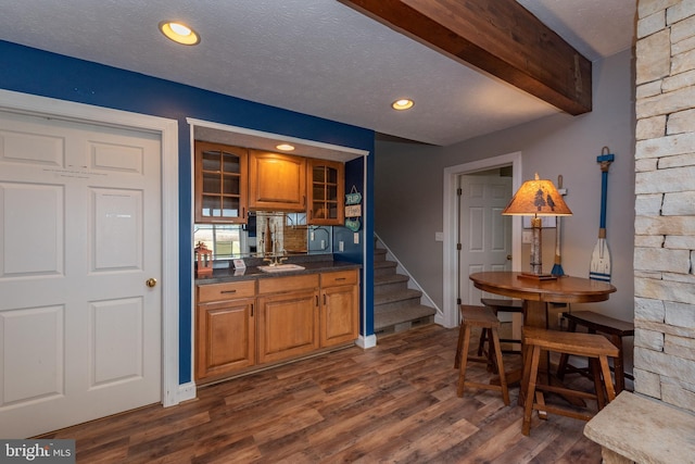 bar featuring a textured ceiling, sink, dark wood-type flooring, and tasteful backsplash