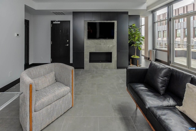 living room featuring a tiled fireplace and light tile patterned flooring