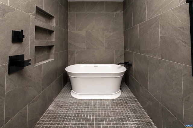 bathroom with tile patterned floors, a bathtub, and tile walls