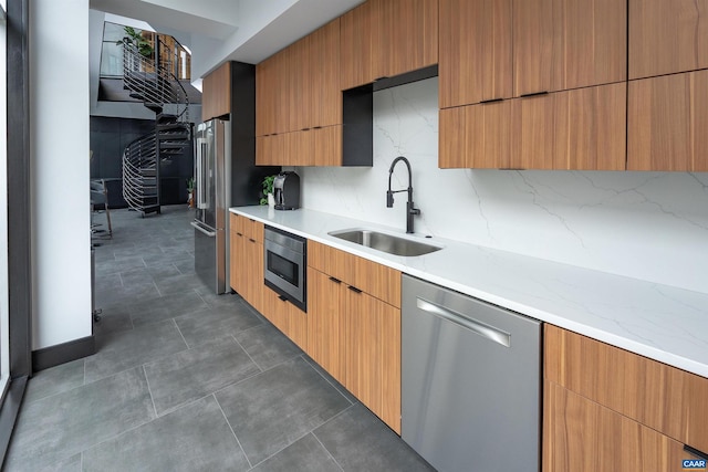 kitchen featuring backsplash, sink, light stone countertops, and stainless steel appliances