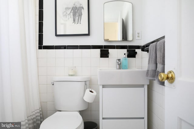 bathroom featuring vanity, toilet, and tile walls