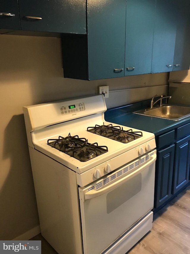 kitchen featuring blue cabinetry, white gas range, light hardwood / wood-style flooring, and sink