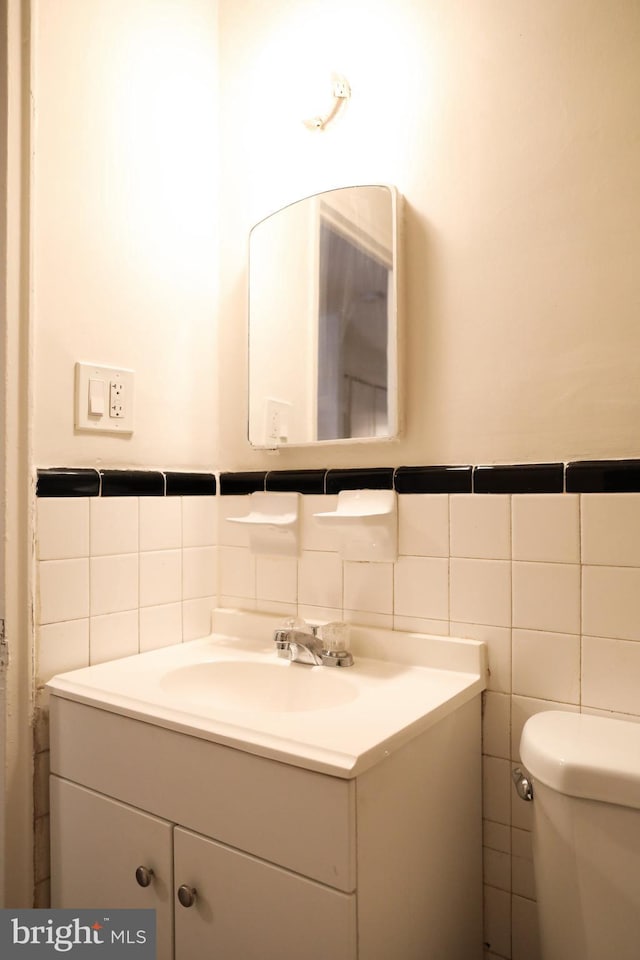 bathroom featuring vanity, toilet, and tile walls