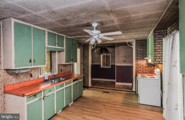 kitchen with brick wall, sink, washer / clothes dryer, and green cabinetry