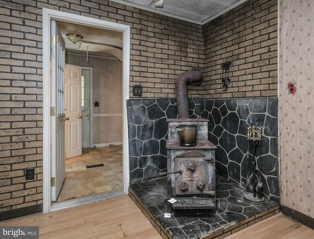 bathroom featuring a wood stove, wood-type flooring, and brick wall