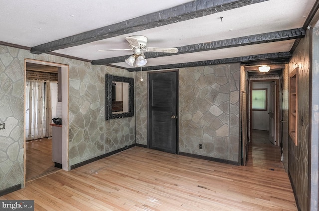 spare room featuring beam ceiling, ceiling fan, and wood-type flooring