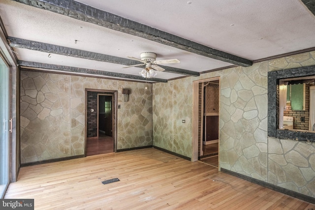 empty room with ceiling fan, hardwood / wood-style floors, beamed ceiling, and a textured ceiling