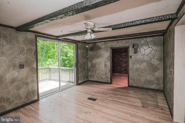 unfurnished room featuring beam ceiling, ceiling fan, hardwood / wood-style floors, and a textured ceiling