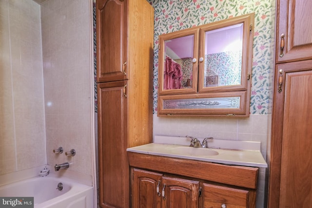 bathroom with vanity, tiled shower / bath, and tile walls