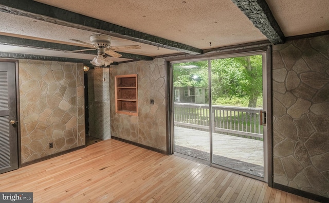 interior space featuring ceiling fan, beam ceiling, light hardwood / wood-style floors, and a textured ceiling