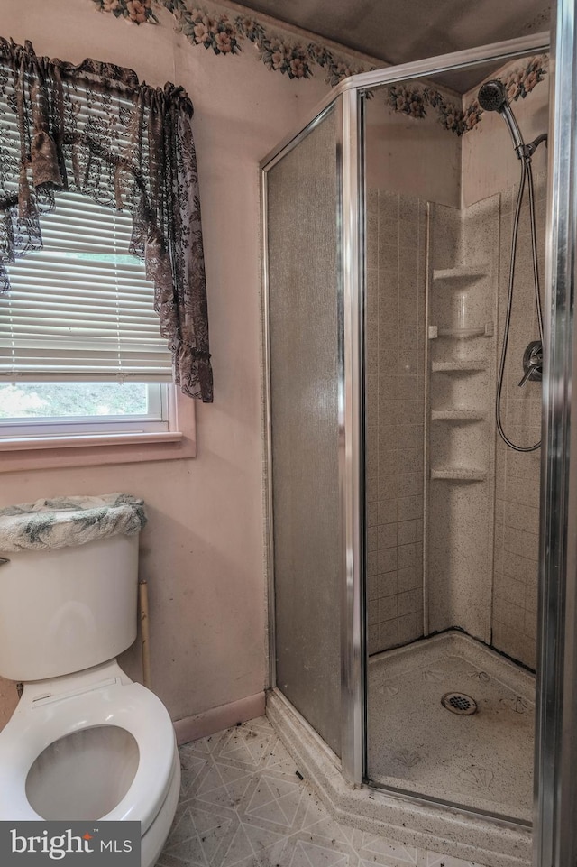 bathroom featuring toilet and a shower with shower door