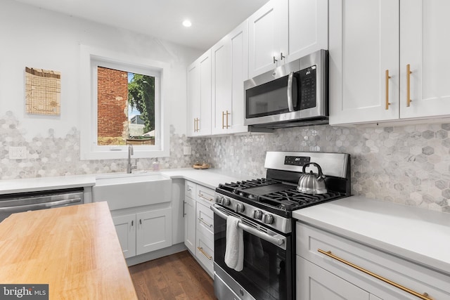 kitchen featuring appliances with stainless steel finishes, sink, white cabinets, and dark hardwood / wood-style flooring