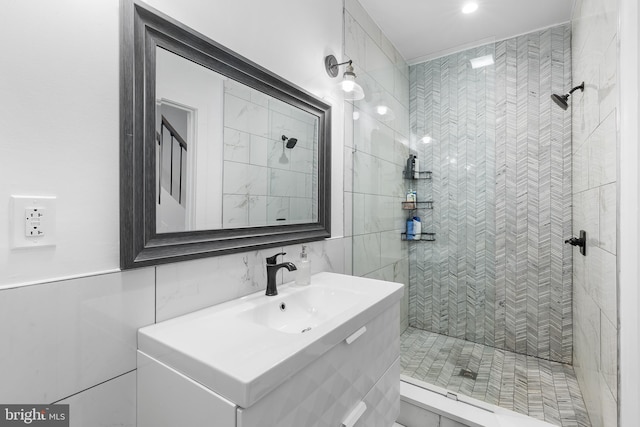 bathroom with tile walls, a tile shower, and vanity