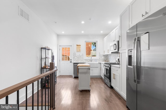 kitchen featuring dark hardwood / wood-style floors, stainless steel appliances, backsplash, white cabinetry, and a center island