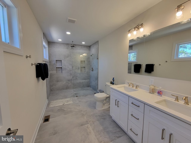 bathroom featuring vanity, toilet, and a tile shower