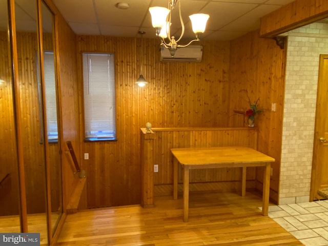 dining space with wood walls, light hardwood / wood-style flooring, and a notable chandelier