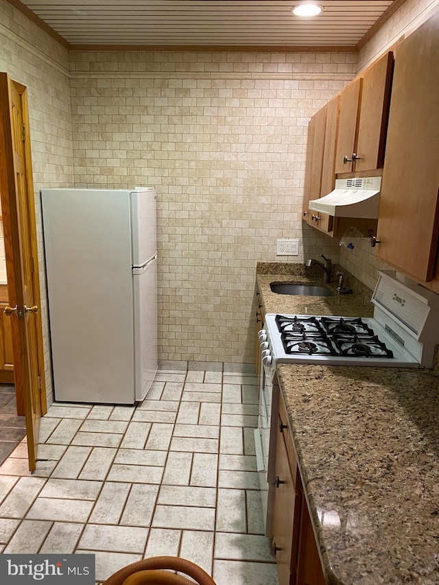 kitchen featuring white appliances, dark stone counters, and sink