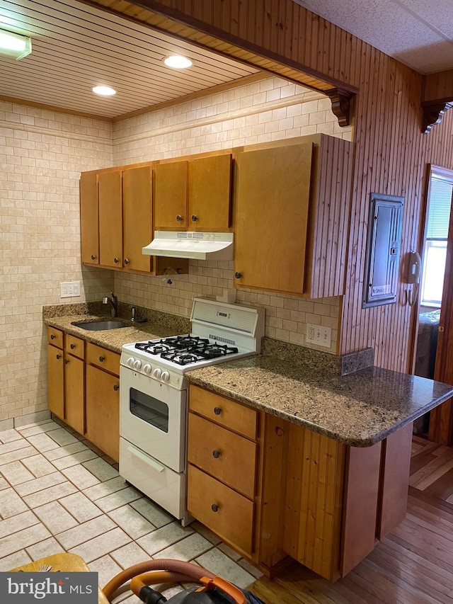 kitchen featuring white range with gas cooktop, sink, and dark stone counters