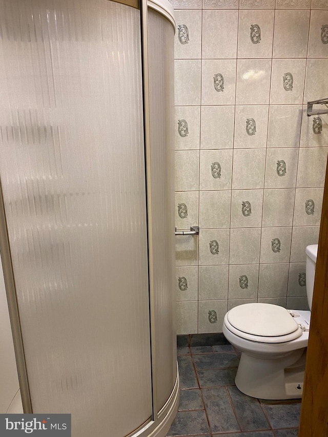 bathroom with tile patterned flooring, toilet, and tile walls