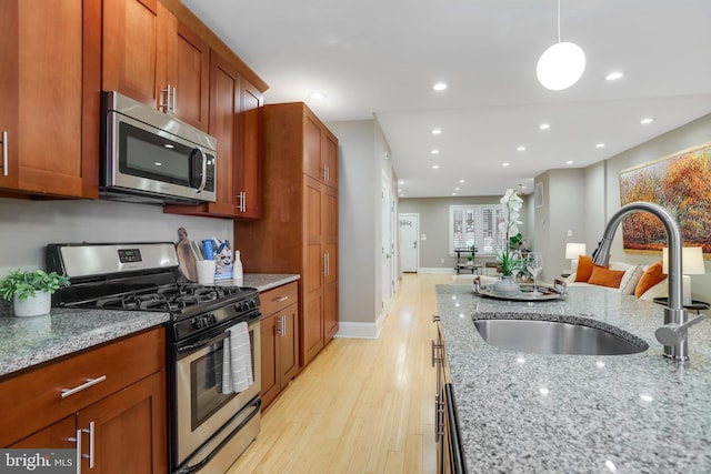 kitchen featuring light stone countertops, decorative light fixtures, stainless steel appliances, and sink