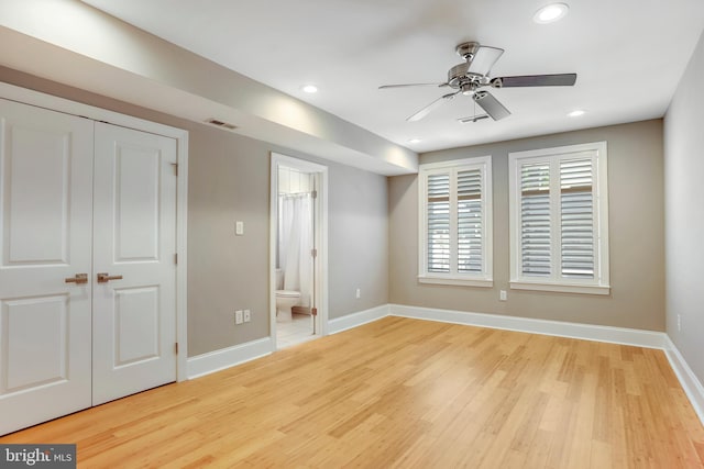 unfurnished bedroom with a closet, ensuite bath, ceiling fan, and light hardwood / wood-style flooring