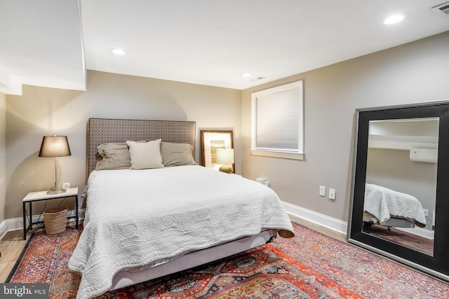 bedroom with an AC wall unit and wood-type flooring