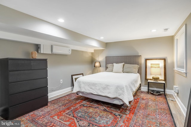 bedroom featuring hardwood / wood-style flooring and a wall unit AC