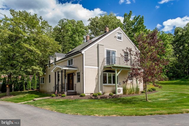 view of front property featuring a balcony and a front yard