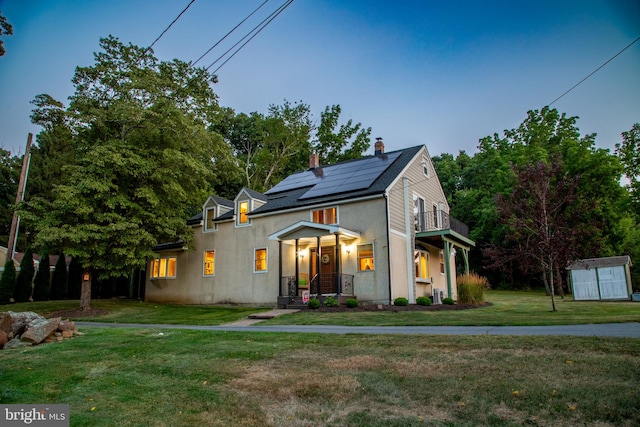 view of front of property with solar panels, a front lawn, and a balcony