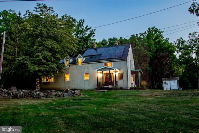 view of front of property featuring solar panels, a storage shed, and a front lawn