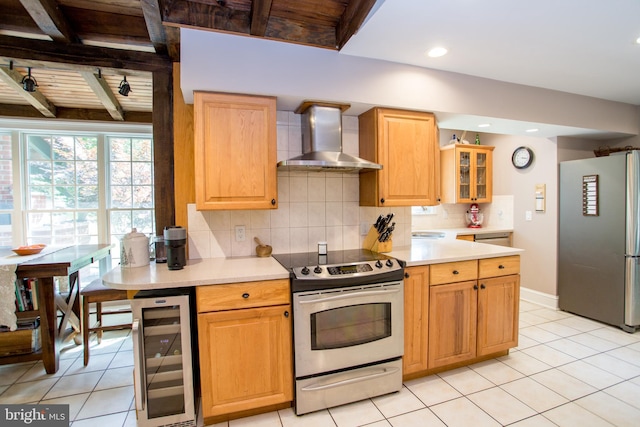 kitchen with backsplash, beamed ceiling, appliances with stainless steel finishes, wall chimney exhaust hood, and light tile patterned floors