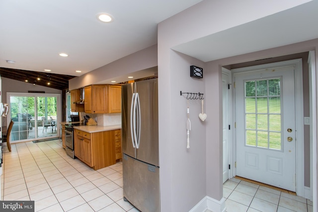 kitchen with decorative backsplash, light tile patterned floors, a wealth of natural light, lofted ceiling, and stainless steel appliances