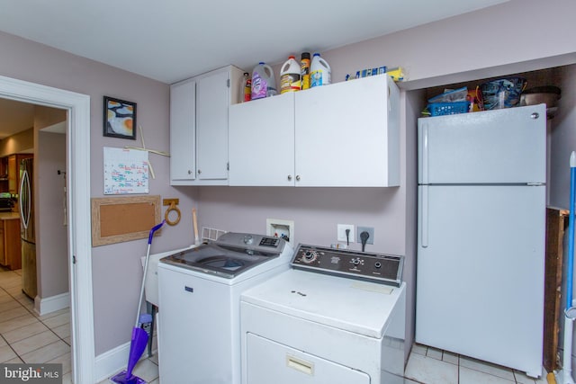 laundry area with light tile patterned floors, washing machine and clothes dryer, and cabinets