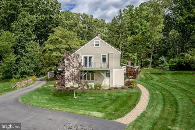 view of front property featuring a balcony and a front yard