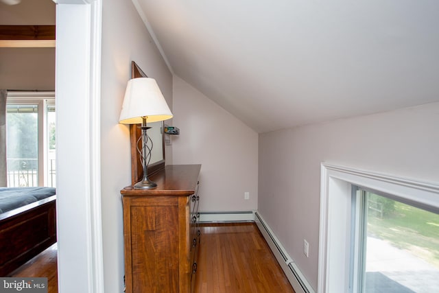 additional living space with vaulted ceiling, a baseboard heating unit, and hardwood / wood-style floors