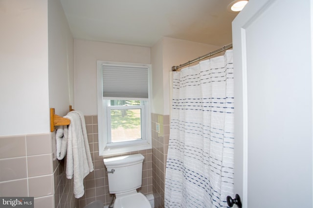 bathroom featuring tile walls and toilet