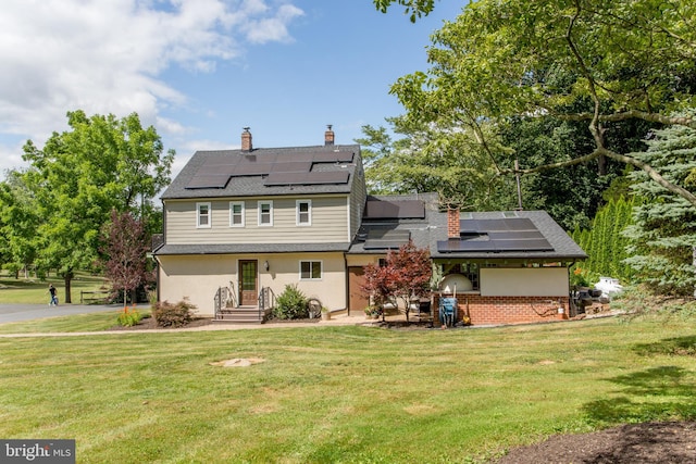 rear view of property featuring solar panels and a yard