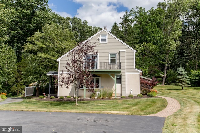 view of front of house featuring a balcony and a front yard