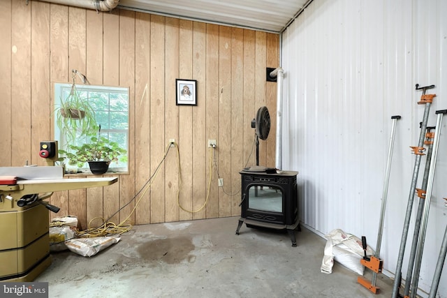 interior space featuring concrete flooring, a wood stove, and wooden walls