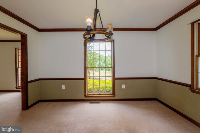 carpeted spare room featuring an inviting chandelier and ornamental molding