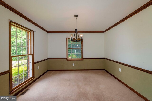 spare room featuring a chandelier, carpet flooring, and crown molding